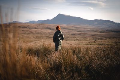 Rear view of man standing on field against sky