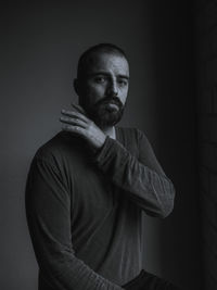 Portrait of man standing against black background