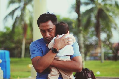 Father carrying new born baby while standing outdoors