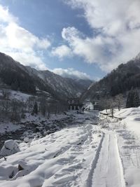 Scenic view of snow covered mountains against cloudy sky