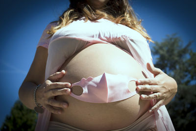 Seven months pregnant woman with baby mask over her gut. pink color