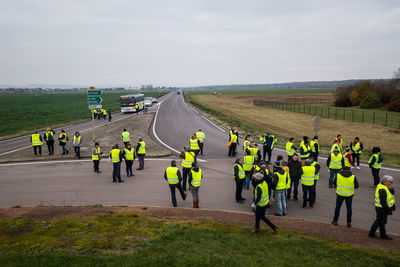 People in reflective clothing on road during yellow vests movement against sky