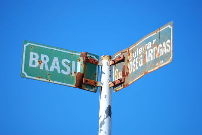 Low angle view of road sign against blue sky