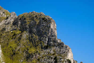 Low angle view of rocks against clear blue sky