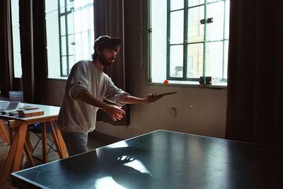 Young man playing table tennis in room