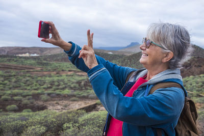 Portrait of woman using mobile phone against sky