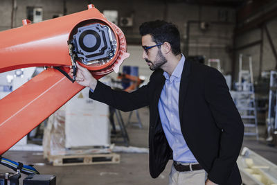 Engineer examining robotic arm in industry