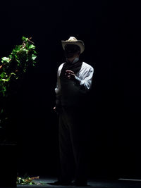 Portrait of man standing against black background