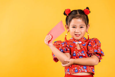 Portrait of cute girl holding toy against yellow background
