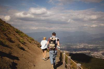 Rear view of people walking on mountain against sky