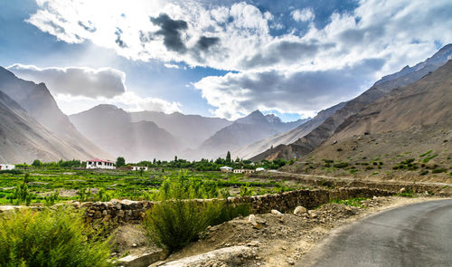 Scenic view of road by mountains against sky