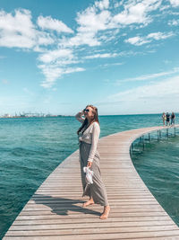 Woman standing by sea against sky