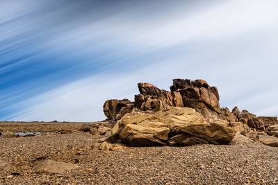 Rock formation on beach against sky. long exposure