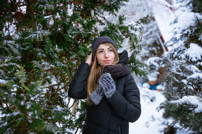 Portrait of young woman standing against trees