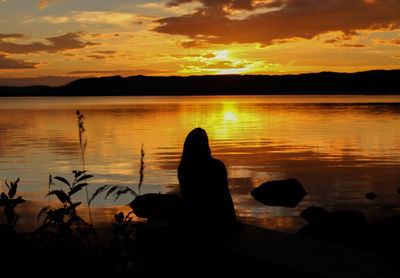 Silhouette people on lake during sunset