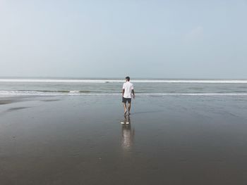 Rear view of man walking at beach