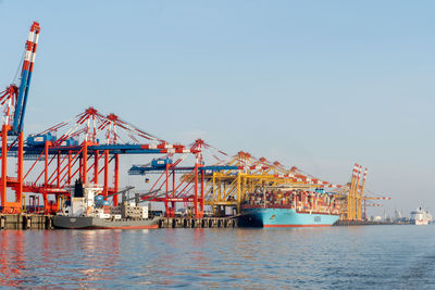 Cranes at commercial dock against clear sky