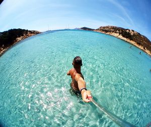 Rear view of shirtless man in sea against sky