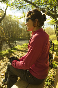 Side view of happy woman sitting on bench at park