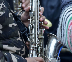 Midsection of musicians playing saxophone for performance outdoors