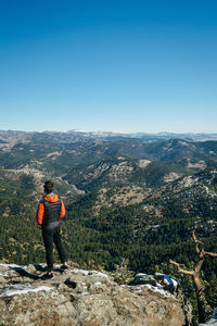 Rear view of man standing on mountain against sky