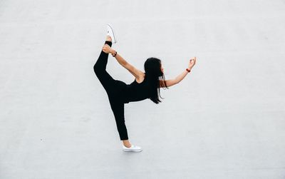 Full length of woman doing yoga against white background