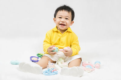 Portrait of cute baby boy playing with toys against white background