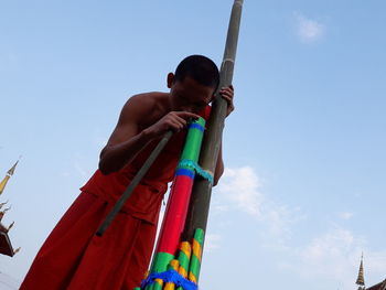 Low angle view of boy standing against sky