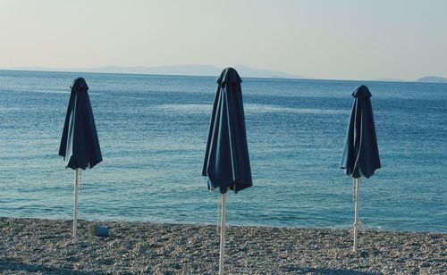 Deck chairs on beach against clear sky