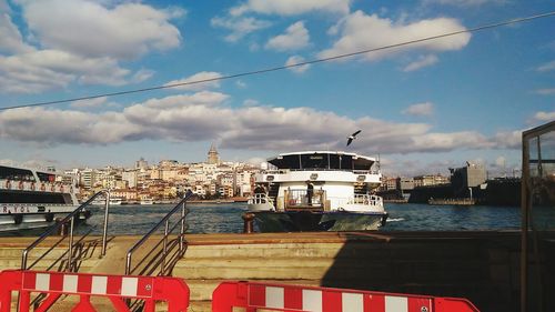 Boats moored at harbor against sky in city