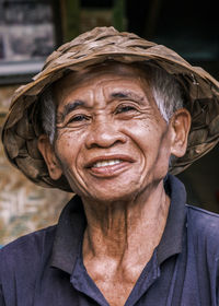 Vertical portrait of south asian balinese senior man wearing a traditional balinese cone-shaped hat.