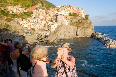 People photographing sea with buildings in background