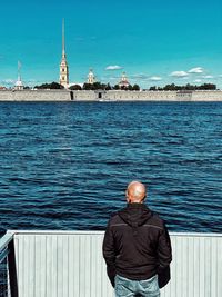 Rear view of man standing by sea against clear sky