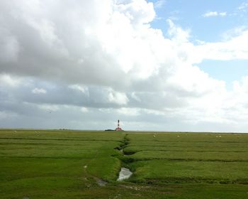 Scenic view of grassy field against cloudy sky
