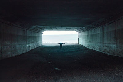 Rear view of silhouette person standing in tunnel against sea