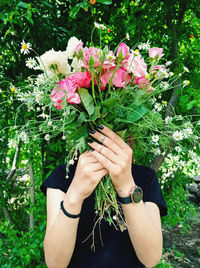 Midsection of woman holding pink flowering plants