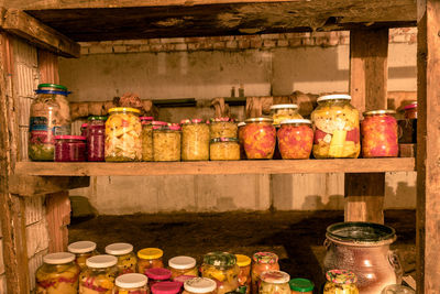 Canned jars in the basement of the house, jars of different shapes on wooden shelves