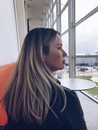 Side view of woman looking through airplane window