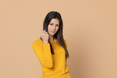 Portrait of woman standing against yellow background