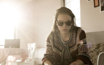 Portrait of young woman wearing sunglasses while sitting at home