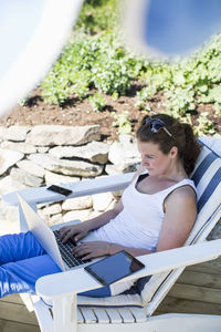 High angle view of woman using laptop on lounge chair