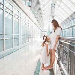 Side view of pregnant mother with daughter standing in corridor