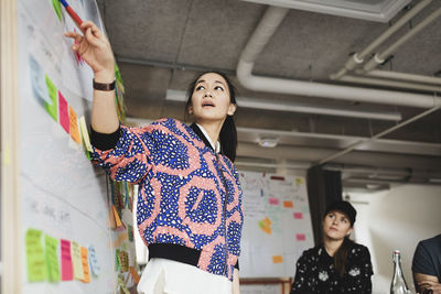 Low angle view of female engineer explaining coworkers during meeting