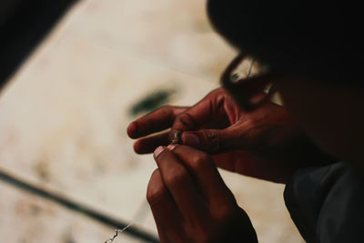 High angle view of person putting bait on fishing rod