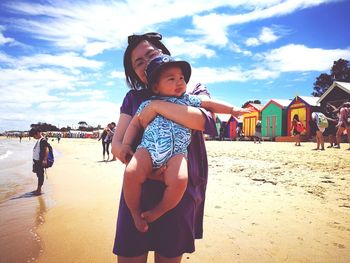 Happy boy standing on beach against sky