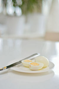 Boiled eggs on a kitchen table, healthy protein rich breakfast. plate, a knife, white background.