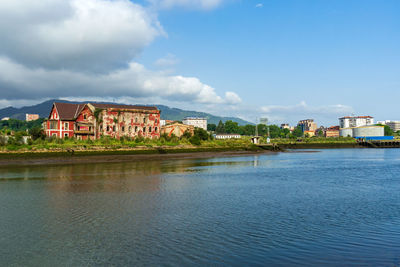 Buildings by sea against sky