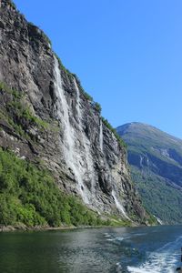 Scenic view of waterfall against clear blue sky