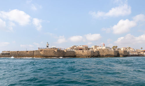 Sea by buildings against sky