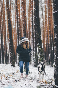 Full length of woman with dog in snow